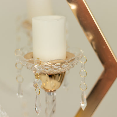 Elegant crystal candle holder with gold accents and dangling prisms.