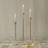 Elegant gold candle holders with glass tubes and candles on a dining table.