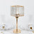 Elegant glass table lamp with gold base, surrounded by dinnerware.