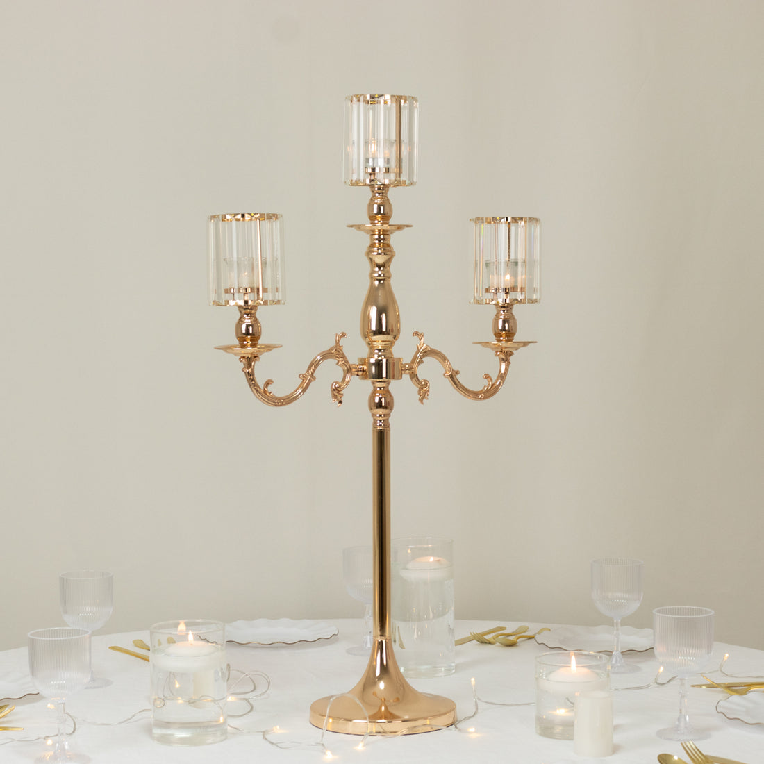 Elegant gold candelabra with crystal holders on a table setting.