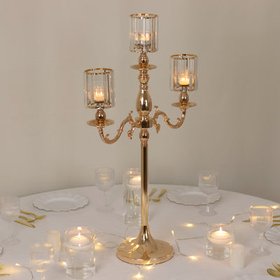 Elegant gold candle holder with glass shades for table decor.