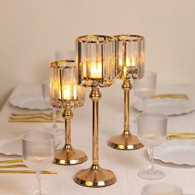 Elegant gold candle holders with lit candles on a dining table setting.