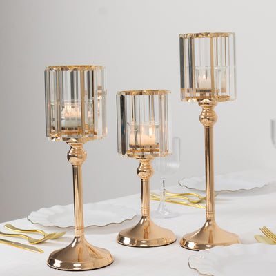 Elegant gold and crystal candle holders in three sizes on a dining table.