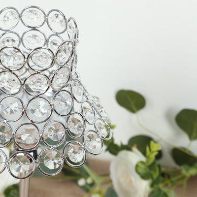 Crystal table lamp with decorative shade and floral backdrop.