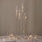 Elegant glass candle holders in varying heights with lit candles on a table setting.
