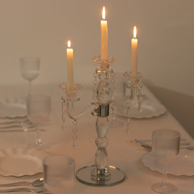 Elegant crystal candle holder with three lit candles on a dining table.