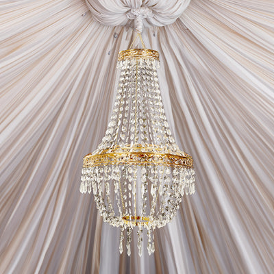 Elegant crystal chandelier with gold accents hanging from draped ceiling fabric.