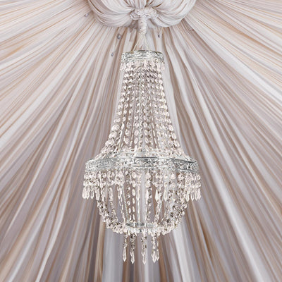 Elegant crystal chandelier hanging from draped fabric ceiling.