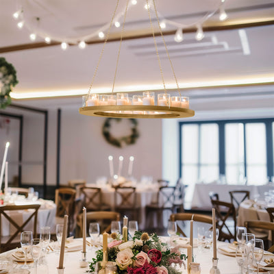 Elegant gold chandelier with candles in a beautifully set dining room.