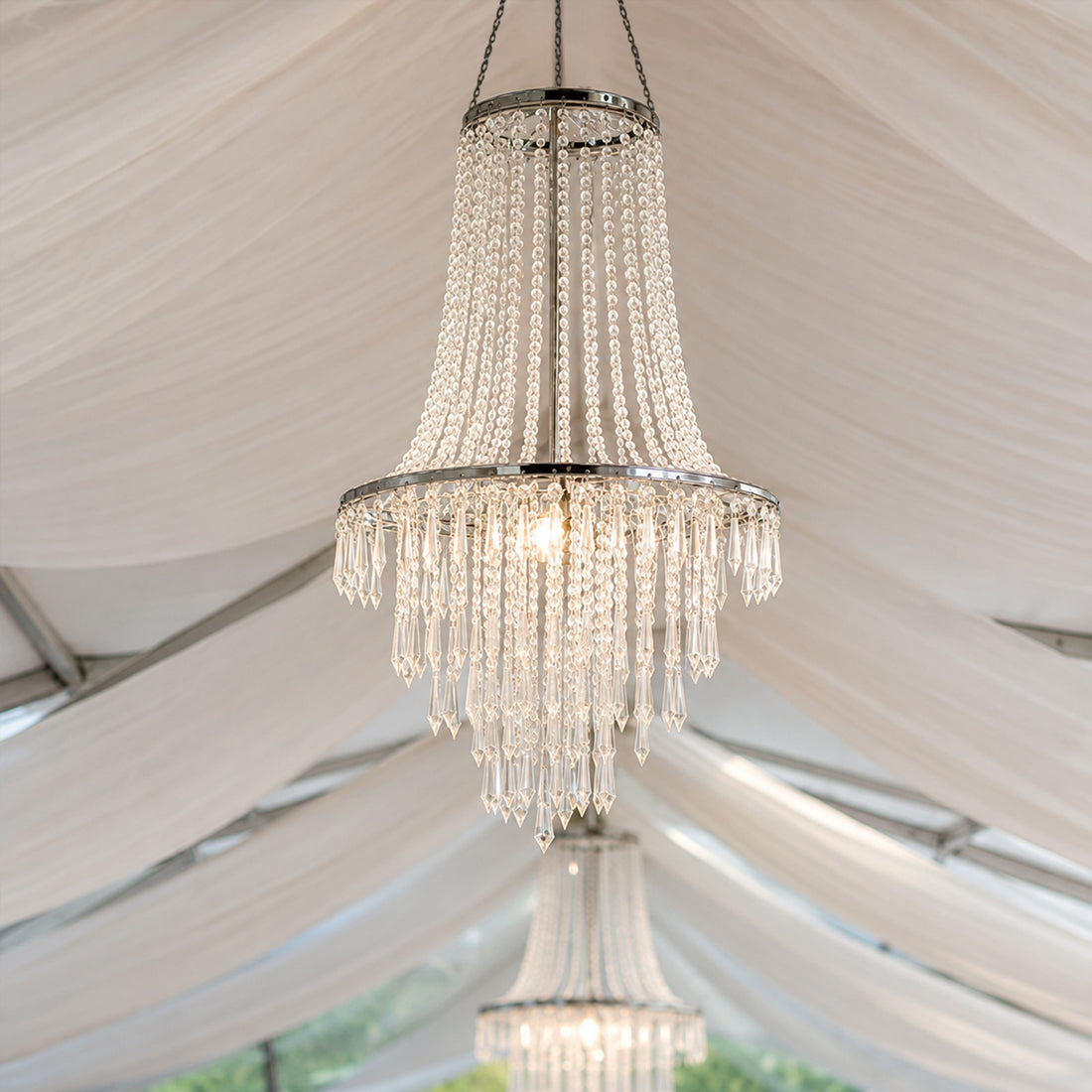 Elegant crystal chandelier hanging under a white tent ceiling
