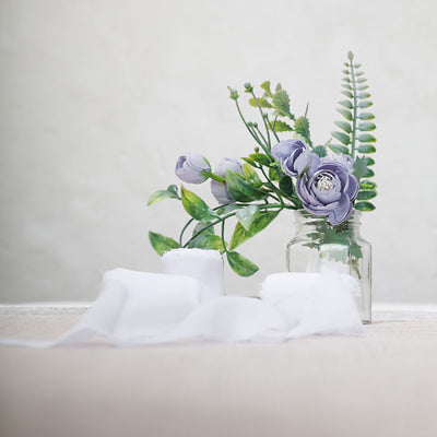 Purple floral arrangement in a glass jar with greenery.