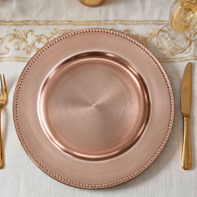 Rose gold beaded charger plate with gold cutlery and champagne glass