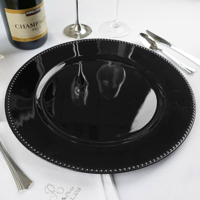 Elegant black charger plate with decorative rim on a white table setting.