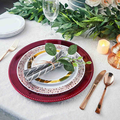 Elegant table setting with burgundy charger plate and silver cutlery.