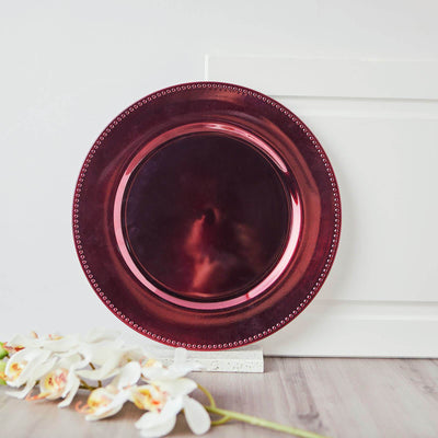 Elegant burgundy charger plate with beaded rim on a white backdrop.