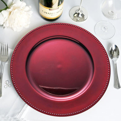 Burgundy charger plate with beaded rim on a dining table setting