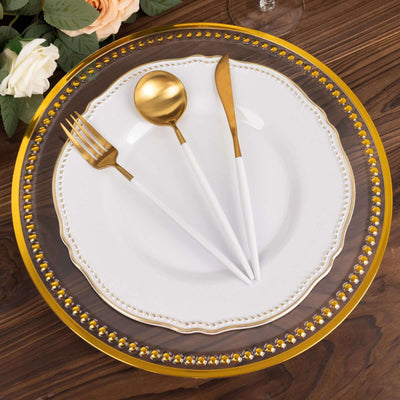 Elegant white plate set with gold utensils on a decorative charger.