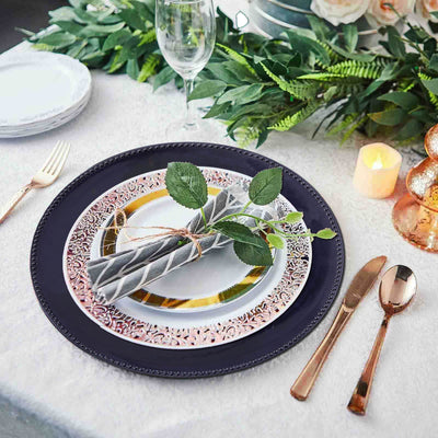 Elegant table setting with navy charger plate, patterned dinner plate, and decorative napkin.