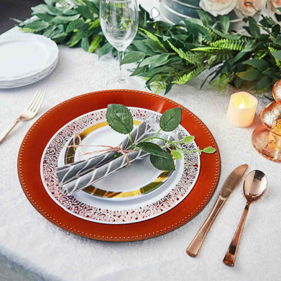 Elegant table setting with decorative plates and napkins, featuring greenery and candles.