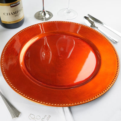 Orange decorative charger plate on a white table setting.
