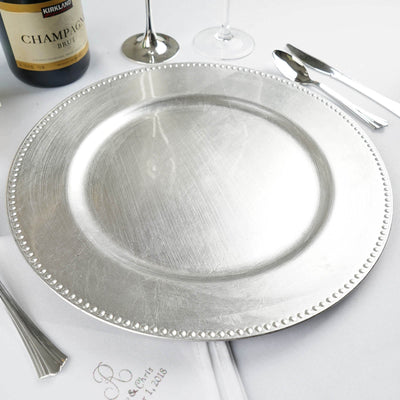 Silver charger plate on a dining table with champagne and glassware.