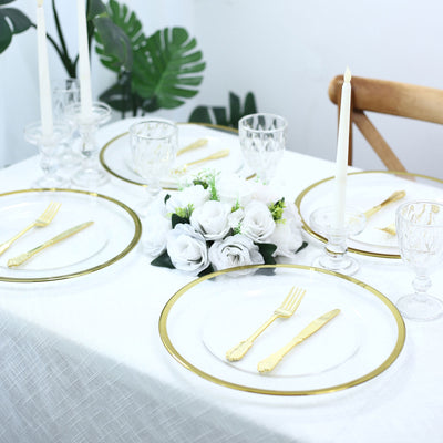 Elegant white and gold table setting with floral centerpiece and candle