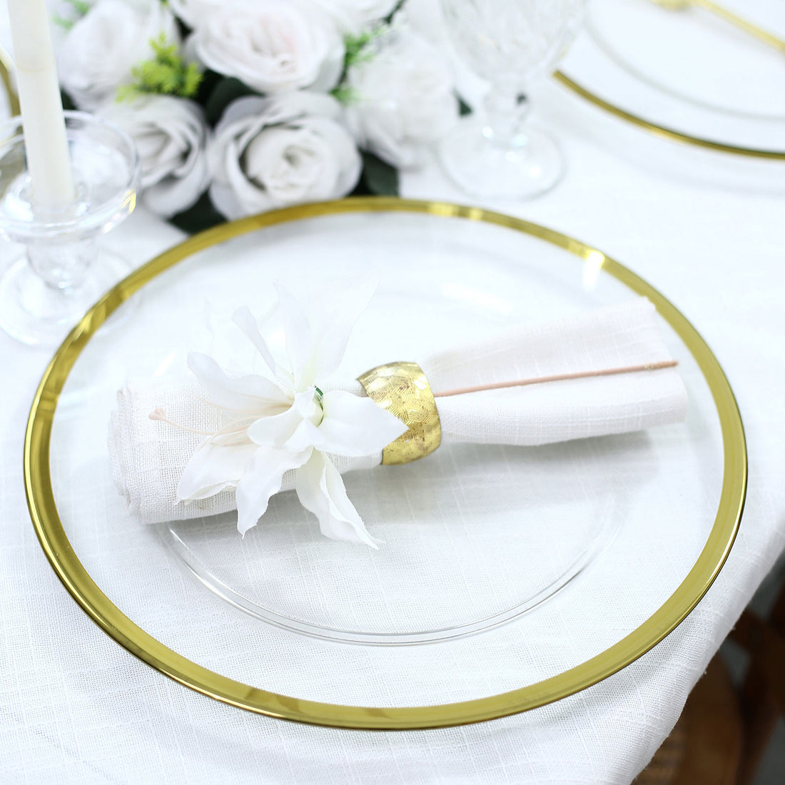 Elegant gold-rimmed charger plate with white napkin and floral decor