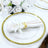 Elegant gold-rimmed charger plate with white napkin and floral decor