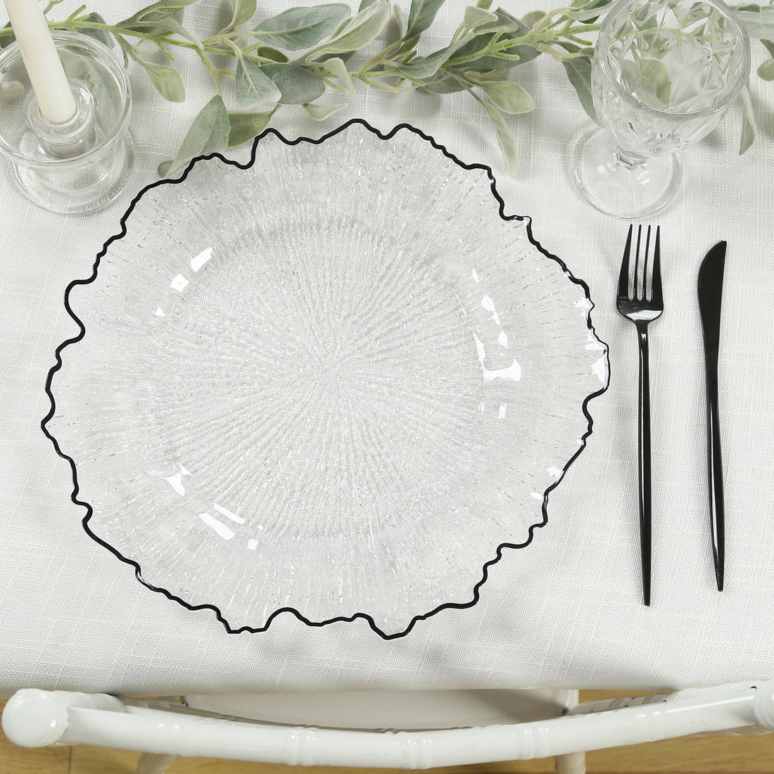 Clear glass plate with black rim on a textured table setting.