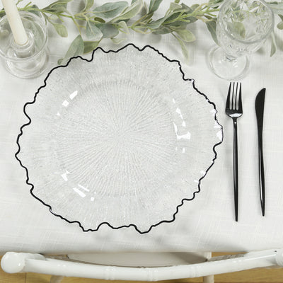 Clear glass plate with black rim on a textured table setting.