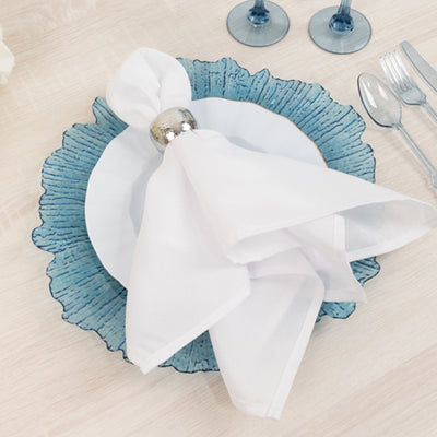 Elegant table setting with blue plate, white napkin, and silver napkin ring.