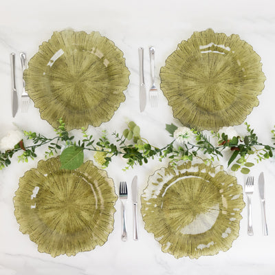 Set of four green glass plates with decorative edges on a marble table.