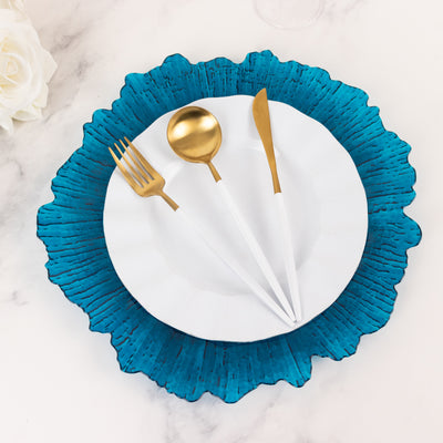 Elegant teal ruffled plate set with gold cutlery on a marble surface.