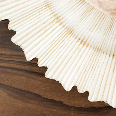 Decorative cream-colored shell plate on a wooden surface.