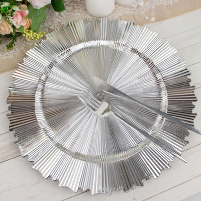Silver fluted serving platter with knife and fork on a table setting.