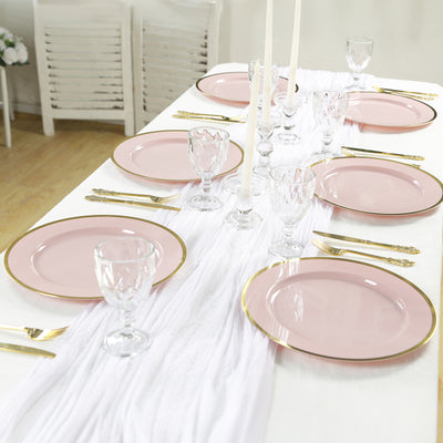 Elegant pink dinner plates with gold rim arranged on a white table setting.
