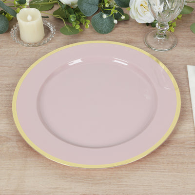 Pink plate with gold rim on a wooden table setting.