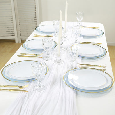 Elegant dinner table set with white plates, gold trim, and crystal glassware.