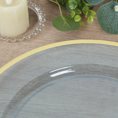 Gray plate with yellow rim on wooden table, surrounded by greenery and candle.