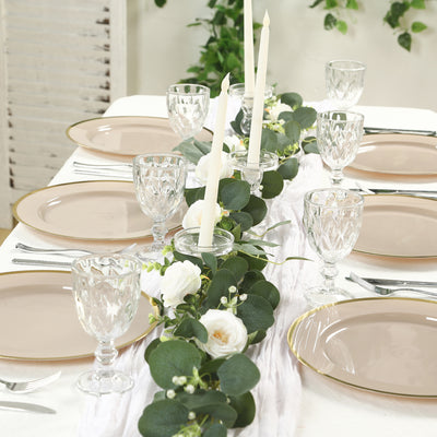 Elegant dining table setting with candles, plates, and greenery.