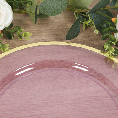 Clear pink plate with a gold rim, surrounded by greenery and flowers.