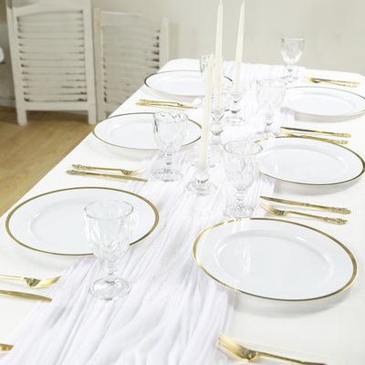 Elegant dining table set with white plates, gold accents, and crystal glassware.