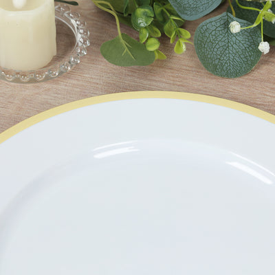 White plate with a gold rim, styled with greenery and a candle.