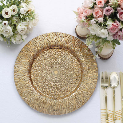 Elegant gold decorative plate with intricate floral pattern, styled with flowers and cutlery.
