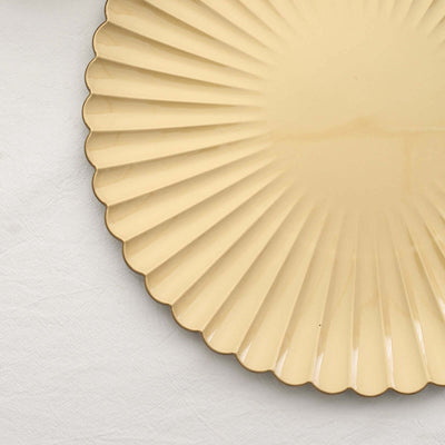 Yellow fluted plate on a textured white background.