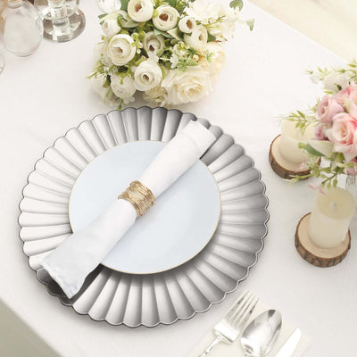 Elegant table setting with silver charger plate, white plate, and floral centerpiece.