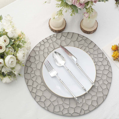 Elegant dining set with decorative plate and silver cutlery on a table.