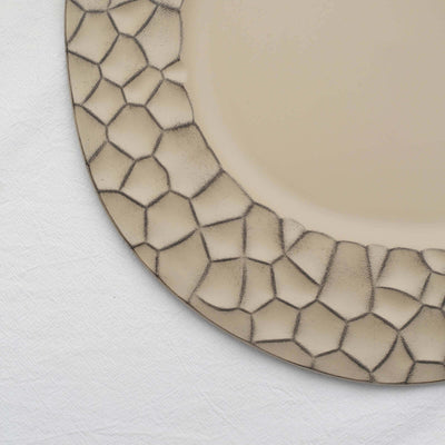 Decorative plate with textured geometric border on a neutral background.