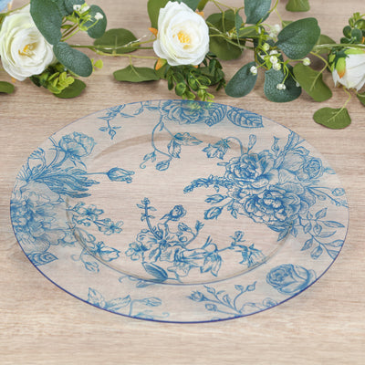 Decorative blue floral plate on a wooden surface with greenery and flowers.