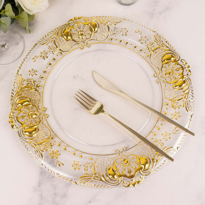 Elegant clear plate with gold floral design, fork and knife on a marble surface.